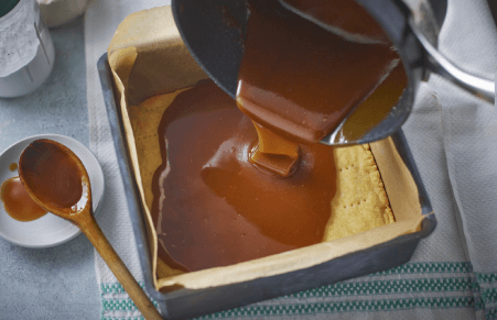 vegan millionaire shortbread caramel being poured over shortbread