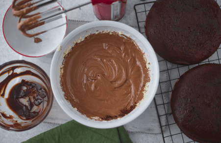 Vegan Chocolate Fudge Cake frosting being made in a bowl with a mixer now with chocolate