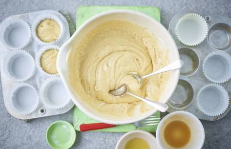 vegan cupcake batter in a bowl being spooned into cupcake cases